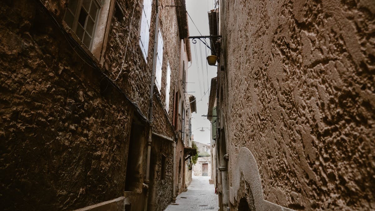 Charming narrow cobblestone street in Le Revest-les-Eaux, France, showcasing rustic architecture.